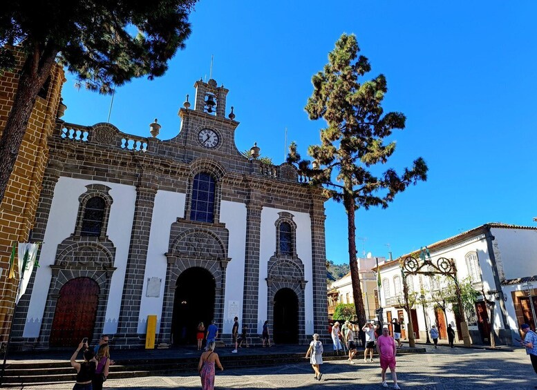 A historic building with a clock tower, arched doorways, and a clear blue sky. 3