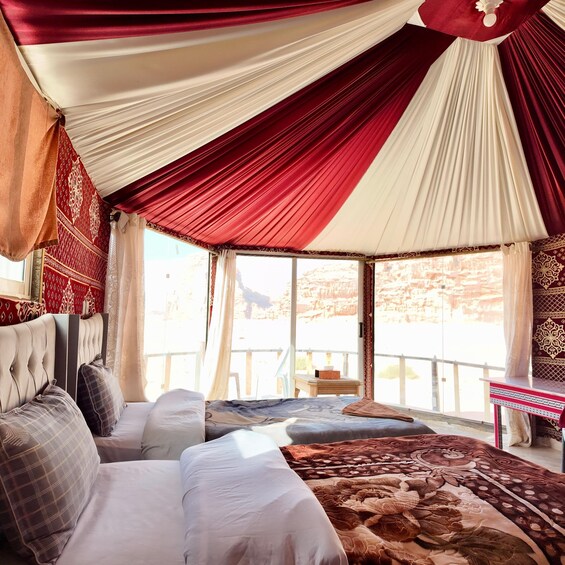 A room with a bed, a table, and a view of a mountainous landscape. 4