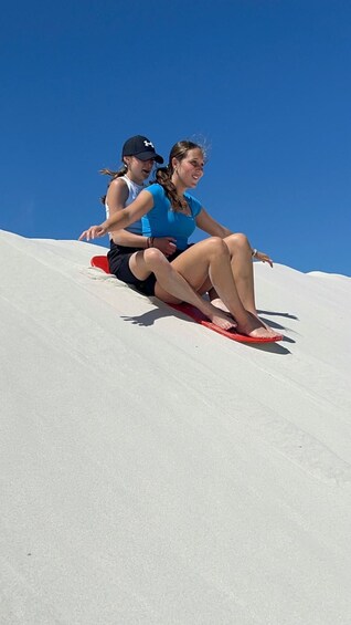 Two people sitting on a red sled on a snowy slope. 2