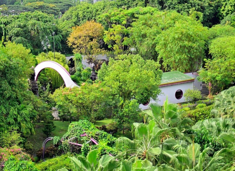 A lush garden with a white gazebo, a curved bridge, and dense greenery. 3