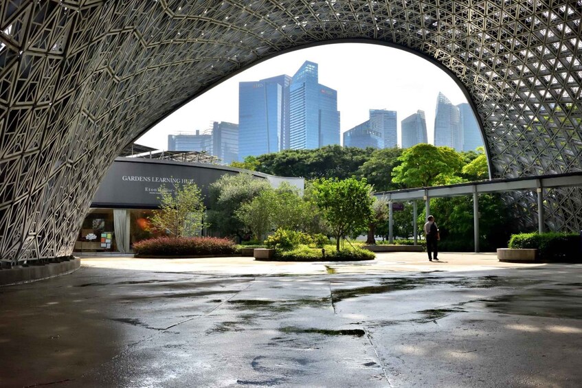 A modern architectural structure with a geometric pattern, a city skyline in the background, and a wet pavement. 5