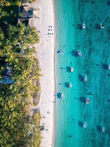 A beach with clear turquoise water, several boats, and a line of palm trees. 1