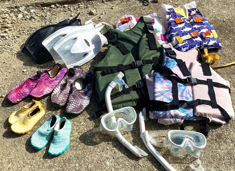 A collection of snorkeling gear, including fins, masks, and a snorkel, laid out on a sandy surface. 4