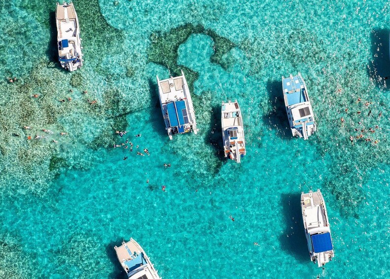 Un grupo de barcos anclados en aguas turquesas cristalinas con arrecifes de coral poco profundos. 4