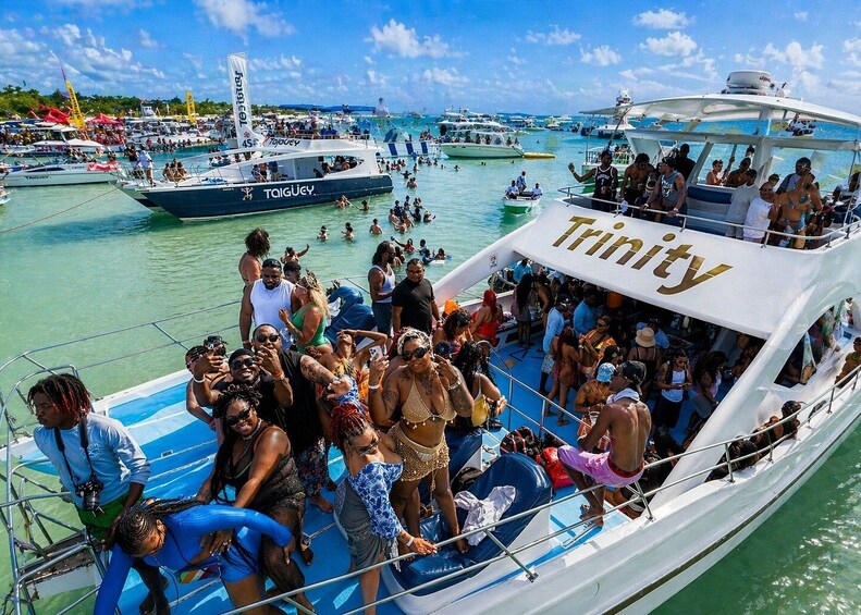 Un bote abarrotado llamado 'Trinity' con pasajeros a bordo y otras personas en el agua. 1