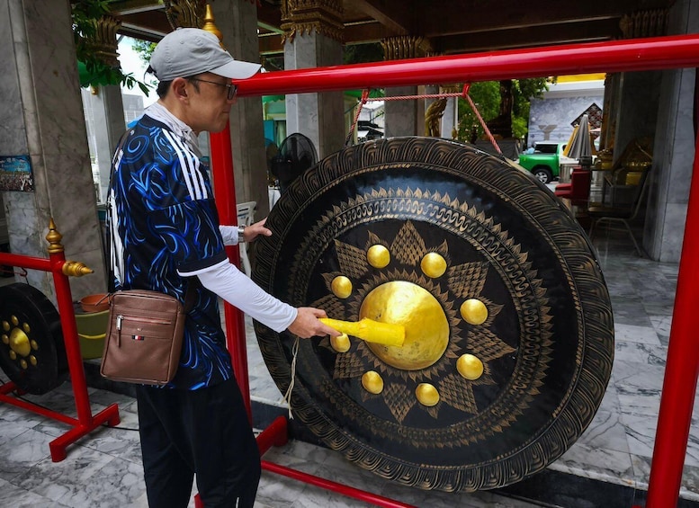 A person interacting with a large, ornate gong in a temple setting. 2