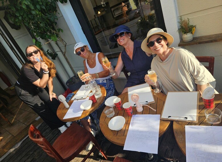 Four people sitting at an outdoor table with drinks, papers, and a clipboard. 1