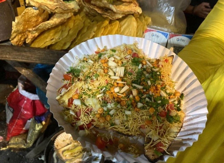 A paper plate with a colorful dish, surrounded by various food items and packaging. 2
