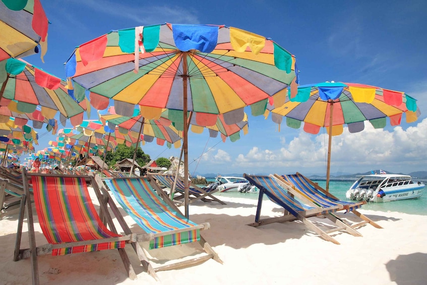 A beach with colorful umbrellas and striped lounge chairs. 2