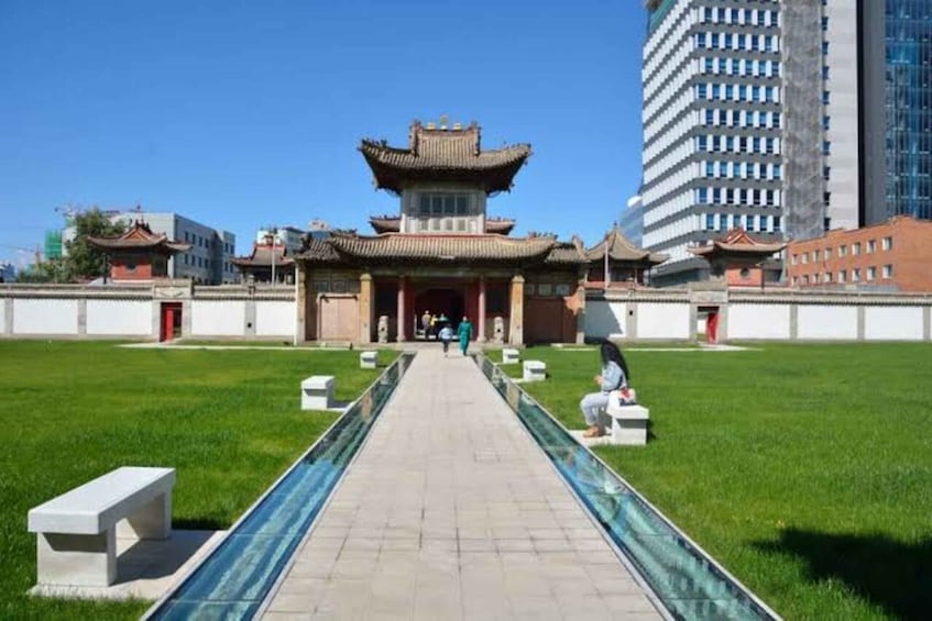 A traditional Chinese building with a tiled roof, a paved walkway, and a grassy area with benches. 3