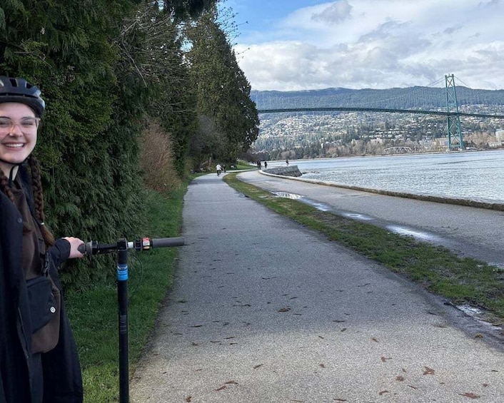 A paved path alongside a river with a bridge in the background. 3