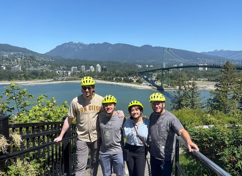 A group of people on a bridge with a cityscape and mountains in the background. 5