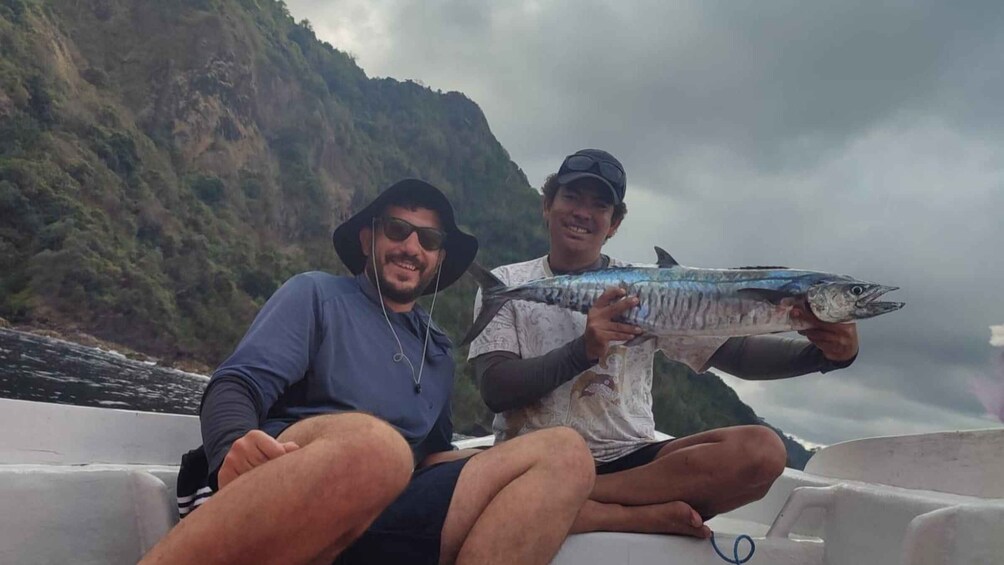 Two people on a boat holding a large fish. 3