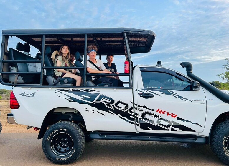 Ein weißes Geländefahrzeug mit den Schriftzügen 'ROCKCO' und 'REVO', ausgestattet mit Offroad-Reifen und einer Dachbox. 3