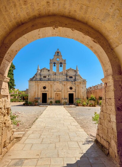 An ancient church with a central bell tower, framed by an arched stone structure. 3