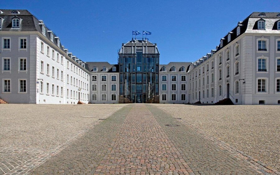 A symmetrical building complex with a central glass structure, flanked by classical architecture. 2
