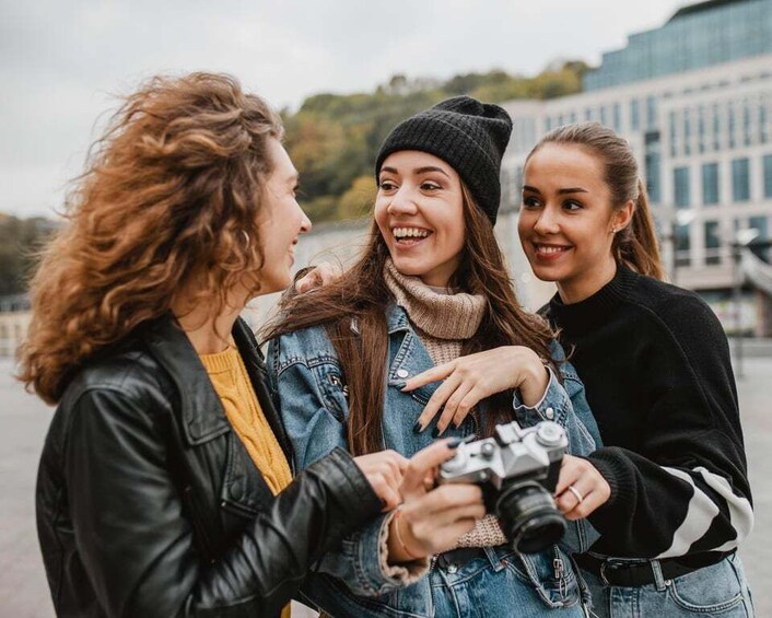 Three people standing outdoors, one holding a camera. 4