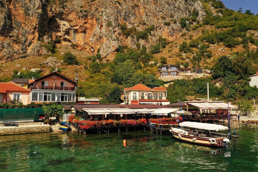 A coastal village with houses, boats, and a rocky cliff. 5