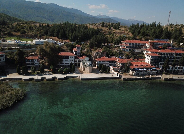 A coastal town with buildings, a marina, and mountains in the background. 2