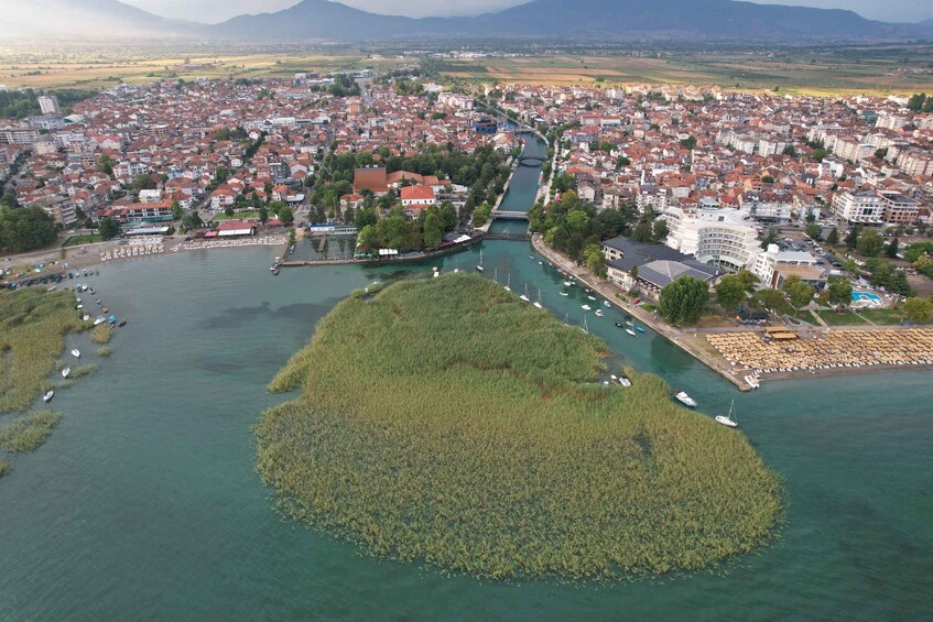 An aerial view of a city with a river, a bridge, and a large green island. 4