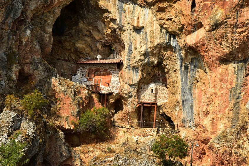 A cave dwelling with a red-tiled roof, nestled within a rocky cliff. 1