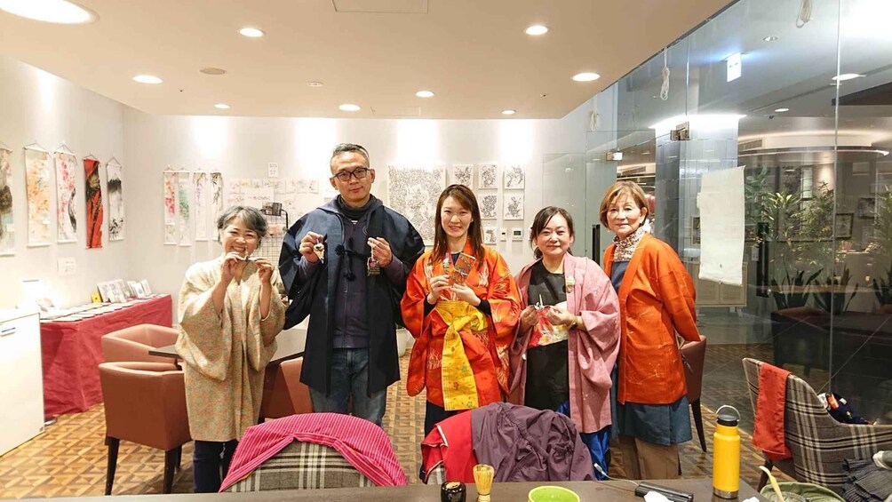 A group of people in a room with art on the walls and a table with items on it. 4
