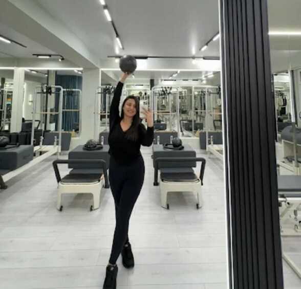 A person exercising with a medicine ball in a gym with exercise equipment. 4