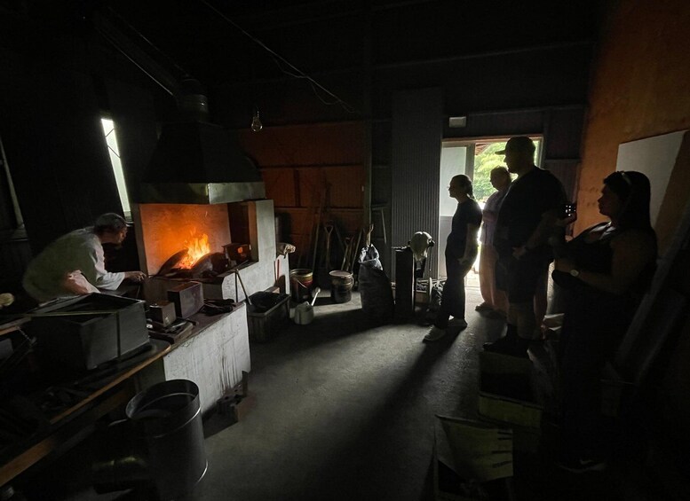 A kitchen with a wood-fired oven, cooking utensils, and people standing around. 5
