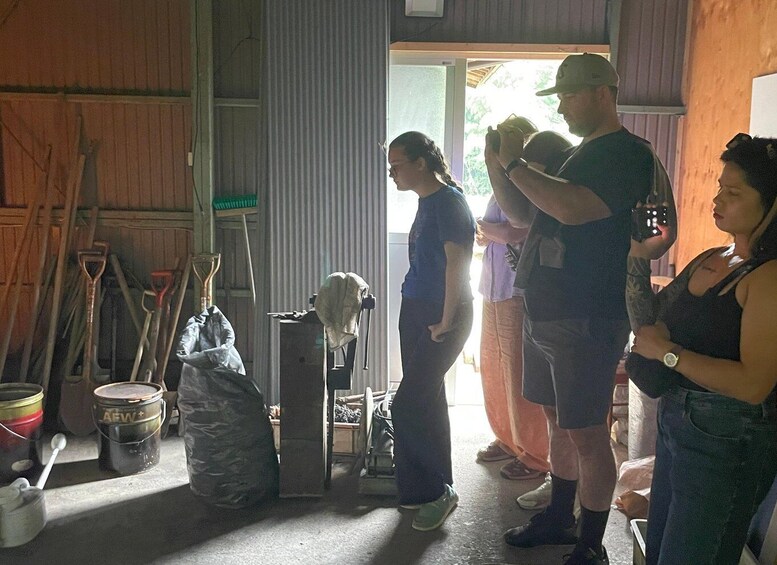 A group of people in a rustic barn with farming tools and equipment. 4