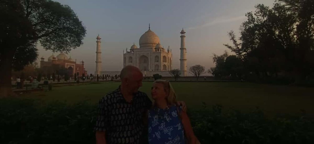A couple standing in front of the Taj Mahal with the Agra Fort in the background. 2