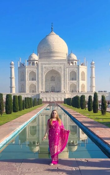 A person in a pink dress standing in front of the Taj Mahal. 5