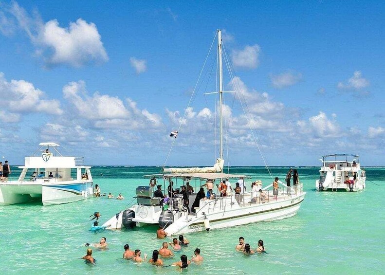A group of people swimming and a boat with passengers in clear turquoise waters. 4