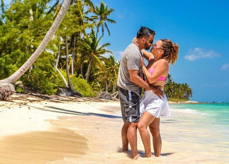 A couple embracing on a beach with palm trees and clear blue water. 5