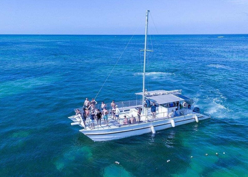A sailboat with people on board, floating on clear blue water. 1