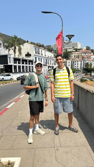 Two people standing on a sidewalk with buildings and a street in the background. 4