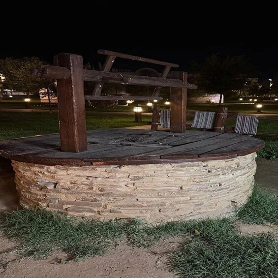 A stone structure with a wooden bench and a cross. 3