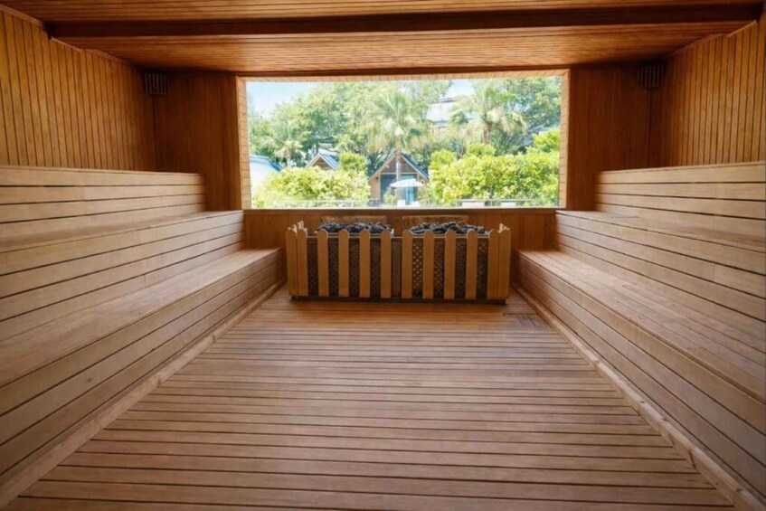Een sauna met houten banken en uitzicht op een traditioneel huis door een raam. 3