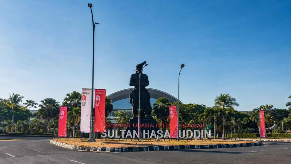 A statue of a man with a sword, surrounded by palm trees and a large archway with banners. 4