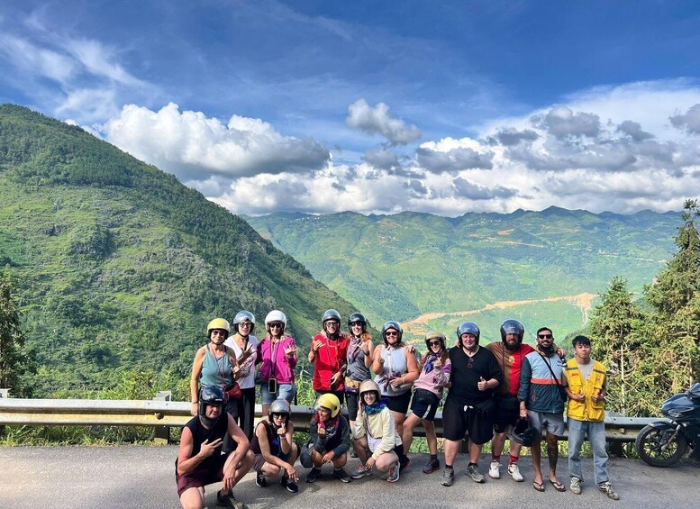 A group of people posing on a road with a mountainous landscape in the background. 2