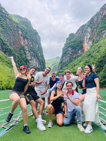 A group of people posing on a boat in a canyon with steep cliffs. 1