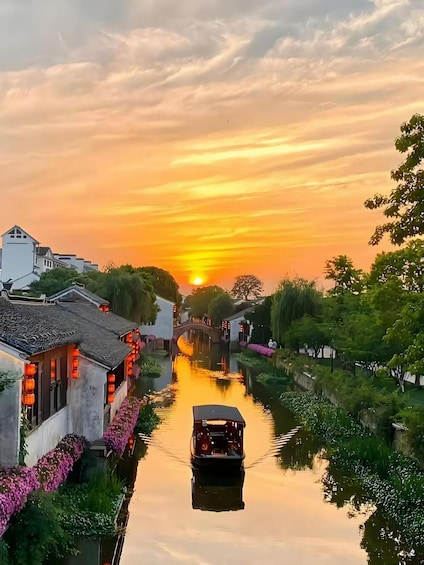 A river at sunset with traditional buildings on one side and a boat in the water. 1