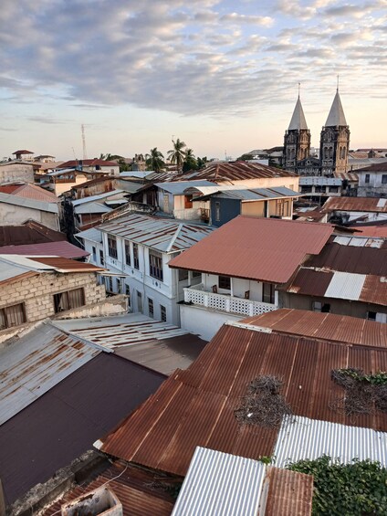 A densely packed urban area with a mix of residential and commercial buildings, featuring a prominent church with two towers in the background. 4