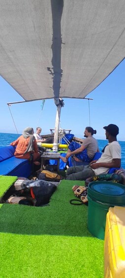 People on a boat with a canopy, green artificial grass, and a blue tarp. 3