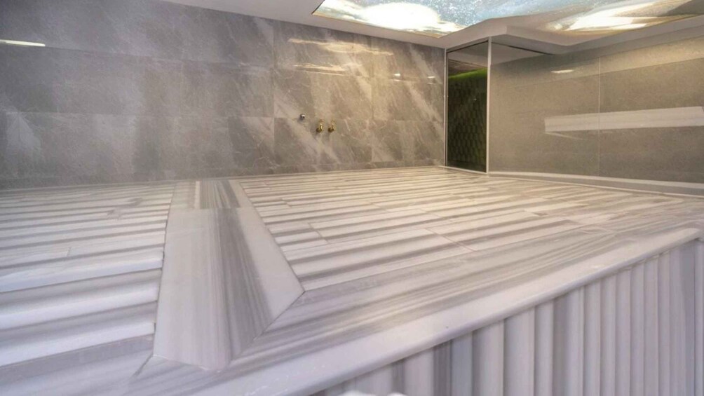 A modern spa with marble floors and walls, a skylight, and a glass door. 2