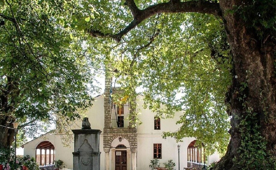 A historic building with a central archway, surrounded by lush green trees. 2