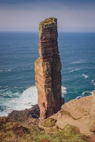 A tall, narrow rock formation by the sea. 4