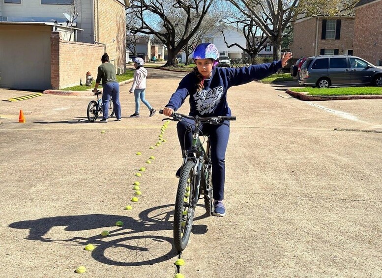 A person riding a bicycle on a street with yellow cones arranged in a line. 2