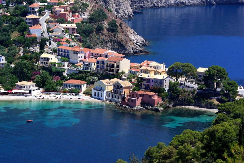 A coastal town with buildings along the shore, clear blue waters, and a rocky cliff in the background. 5