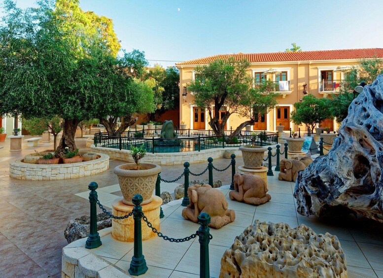 A courtyard with stone sculptures, a fountain, and a building with a tiled roof. 1