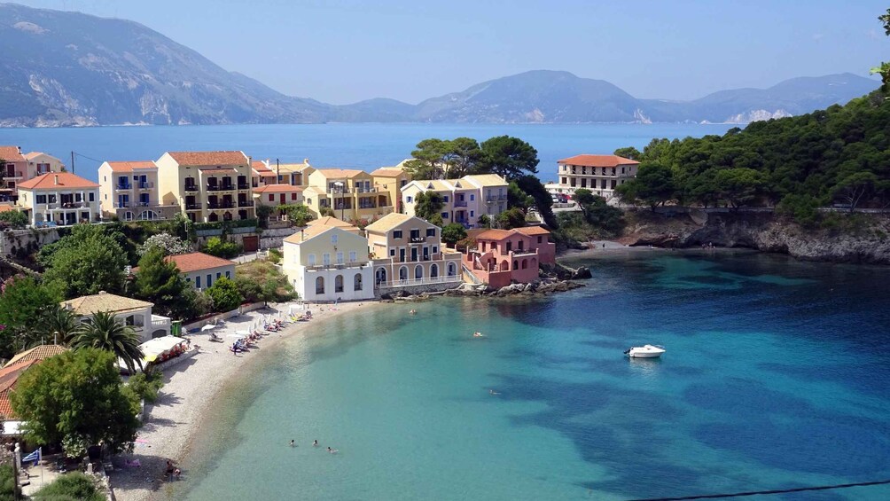 A coastal town with buildings along the shore, clear blue waters, and mountains in the background. 3
